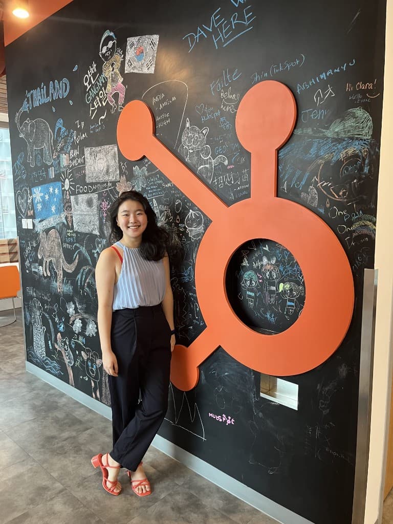 Minu standing beside the HubSpot logo at its Singapore office.