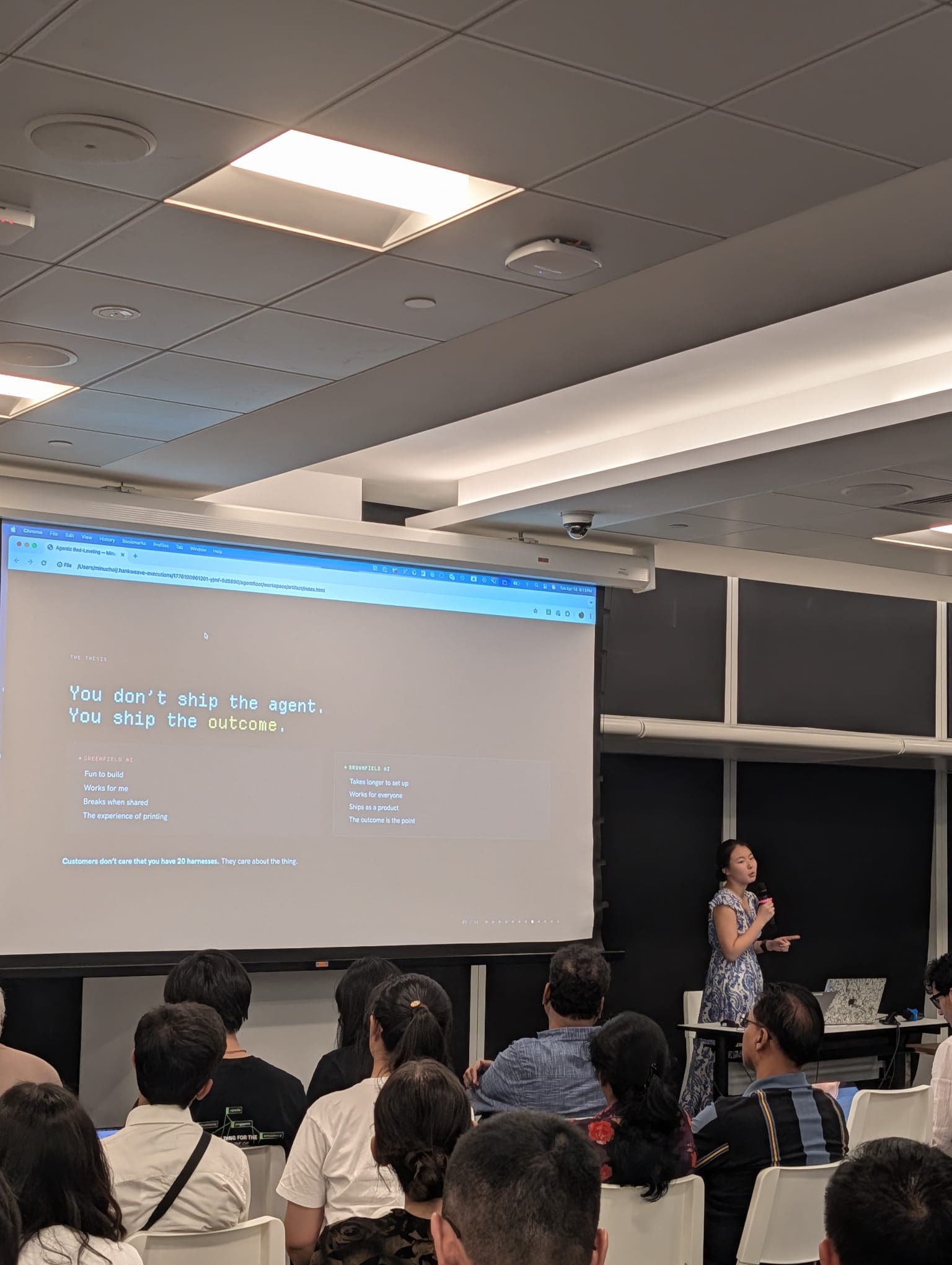 Minu Choi presenting at the National Library, Singapore. The slide reads: You don't ship the agent. You ship the outcome.