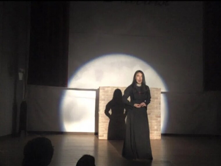 Minu performing on stage with Outburst, under a round spotlight