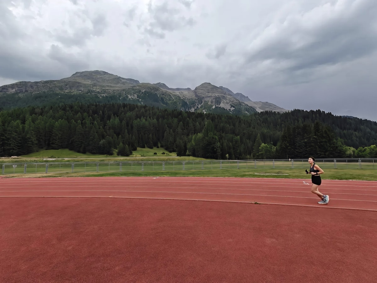 Minu running on an outdoor track beneath the mountains